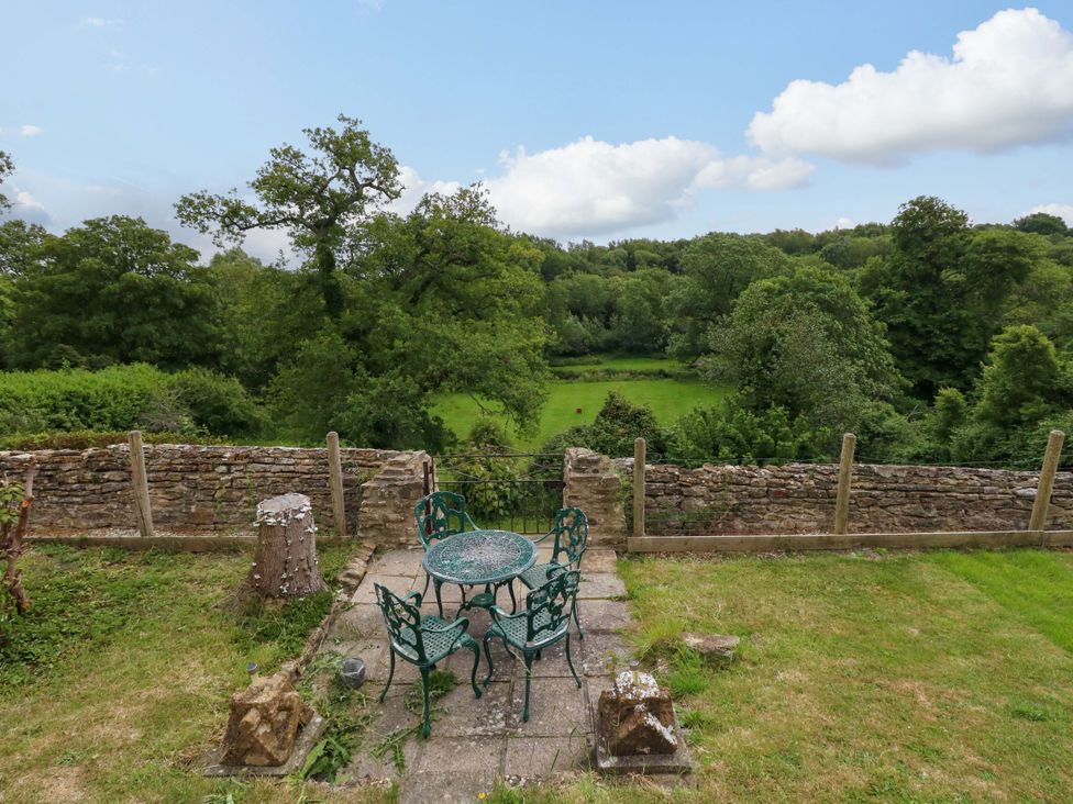 An outdoor area with a table and chairs overlooking a field at Mallows Byre in Yetminster