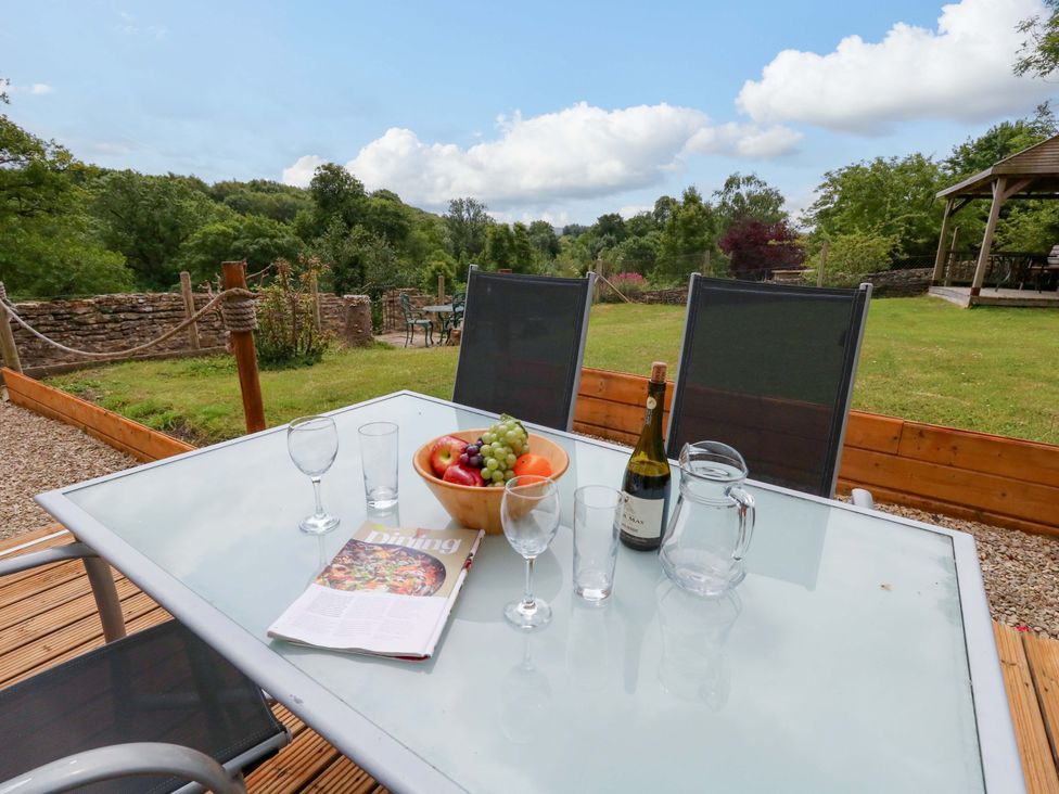 An outdoor dining area with a table set with glasses and fruits at Mallows Byre in Yetminster