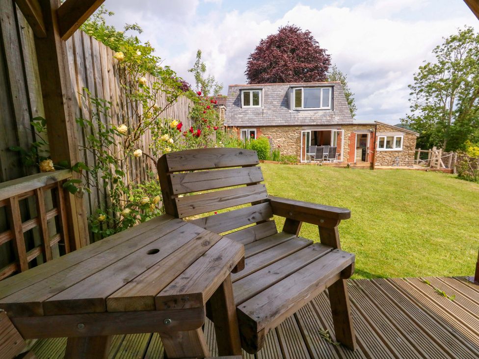 A garden with a wooden chair and table at Mallows Byre in Yetminster