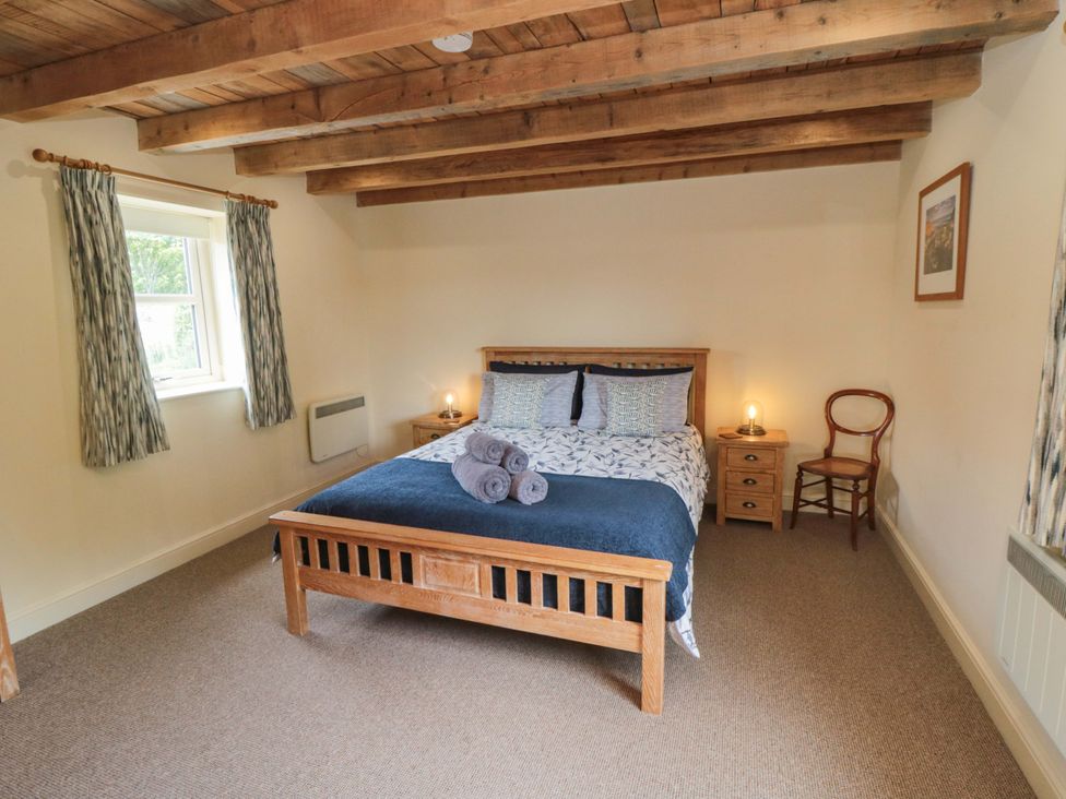 A bedroom with a wooden bed and side table at Field Cottage in Staithes