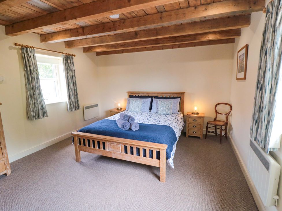 A bedroom with a bed, bedside table and chair at Field Cottage in Staithes