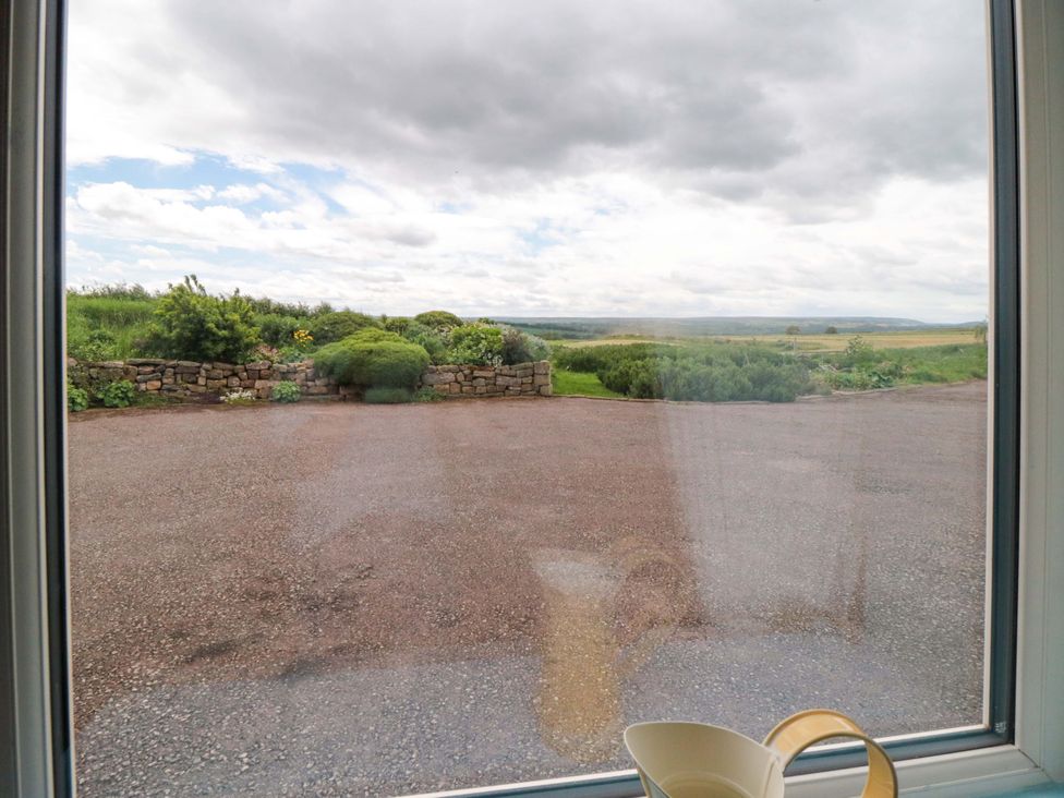 A view of a garden and gravel area from a window at Field Cottage in Staithes