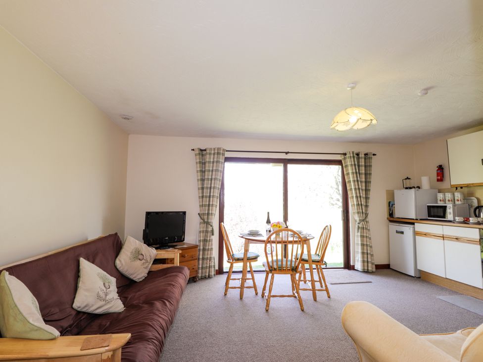 A living room with a dining area and kitchen appliances at Glen Affric View at Hill House, Cannich
