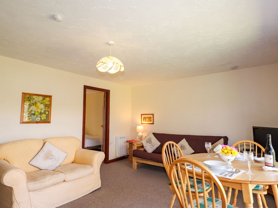 A living room with a couch and dining table at Glen Affric View at Hill House Cannich