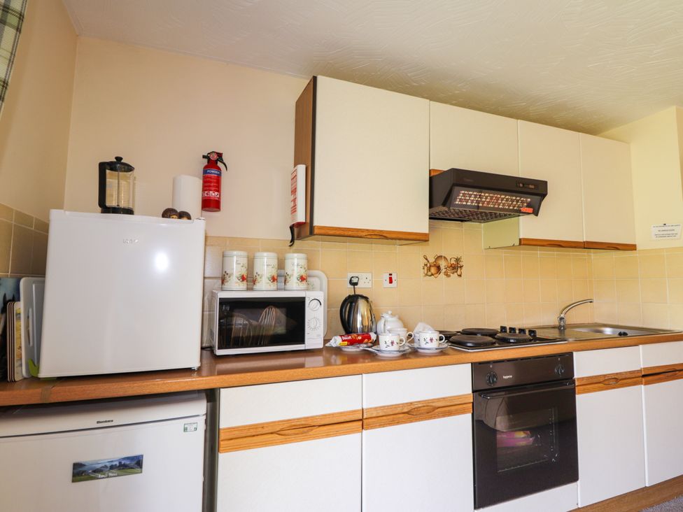 A kitchen with refrigerator, microwave, kettle, and cooktop at Glen Affric View at Hill House in Cannich