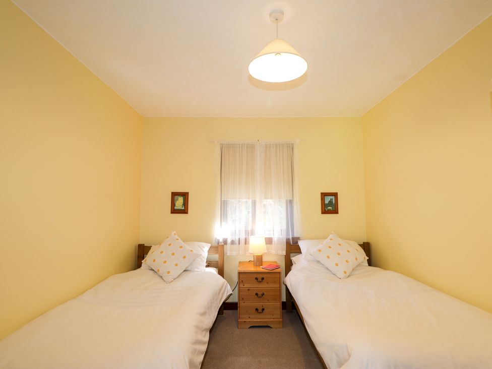 A bedroom with two single beds and a nightstand at Glen Affric View at Hill House Cannich