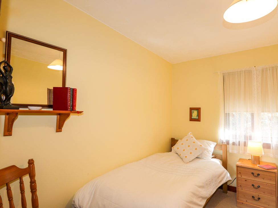A bedroom with a bed and a shelf with books at Glen Affric View at Hill House Cannich