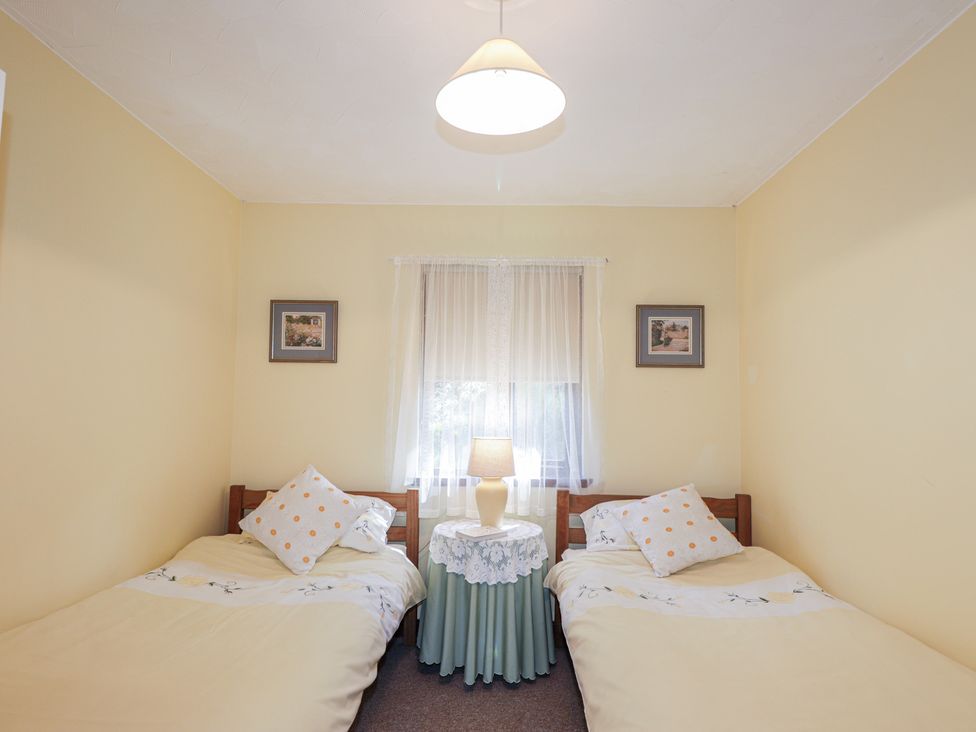 A bedroom with two beds and a lamp at Strath Glass View at Hill House Cannich