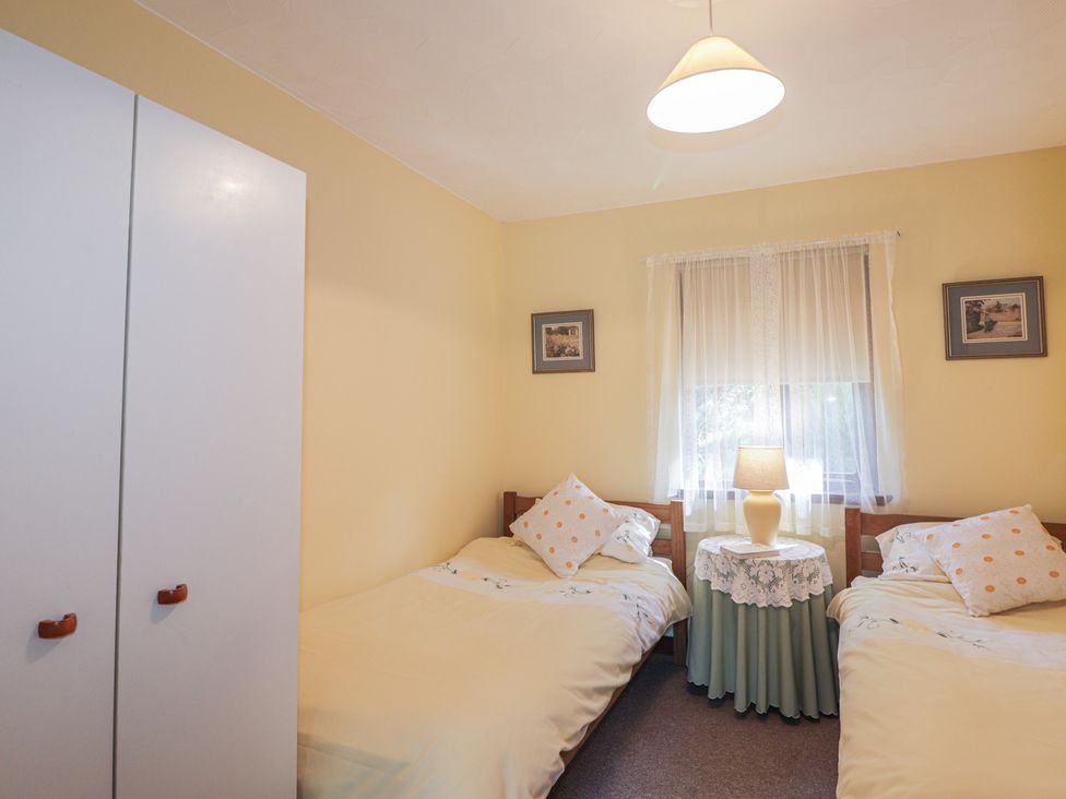 A bedroom with two beds and a lamp at Strath Glass View at Hill House Cannich