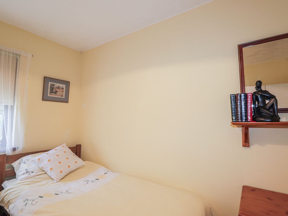 A bedroom with a bed and shelf holding books and a figurine at Strath Glass View at Hill House Cannich