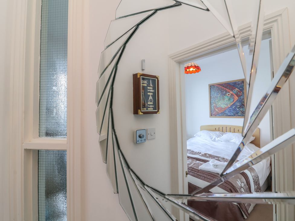 A bedroom with a bed and artwork visible through a mirror at Close to Shore