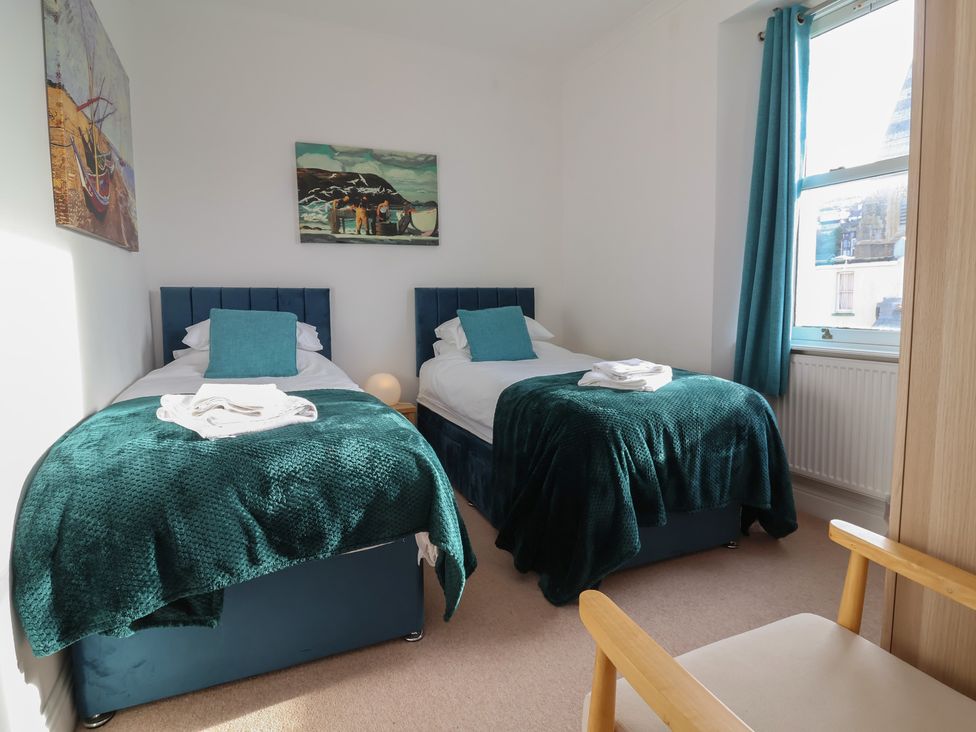 A bedroom with two single beds and artwork on the wall at Close to Shore