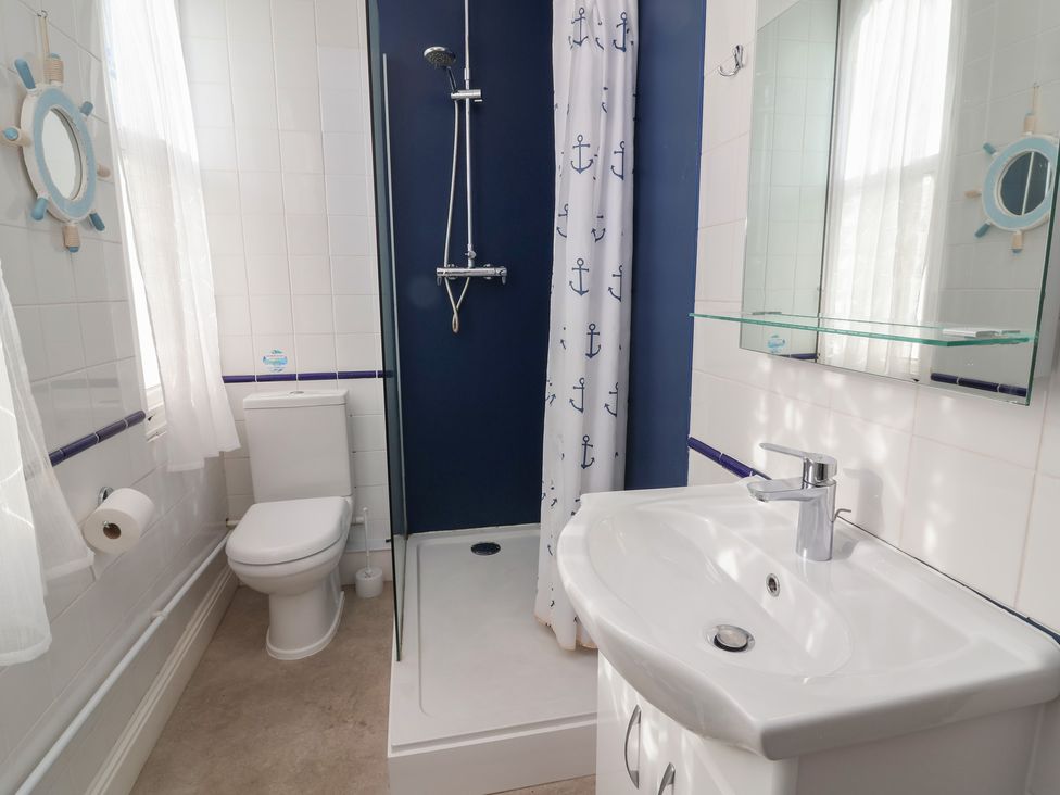 A bathroom with shower, sink, toilet, and mirror at Close to Shore