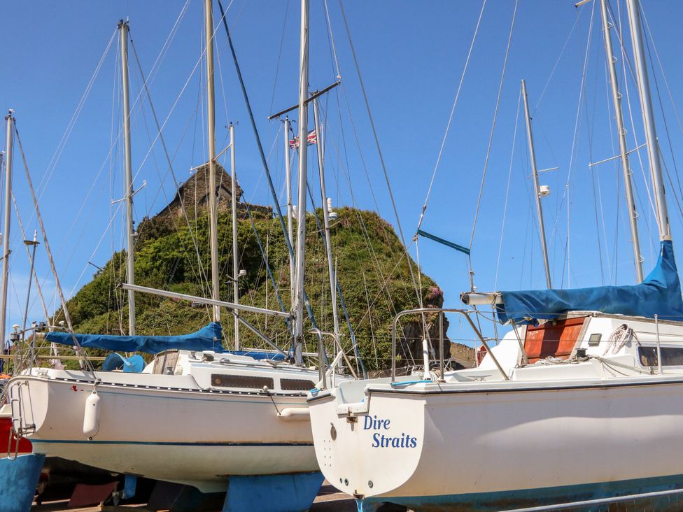Boats at a marina with masts and a hill in the background at Close to Shore