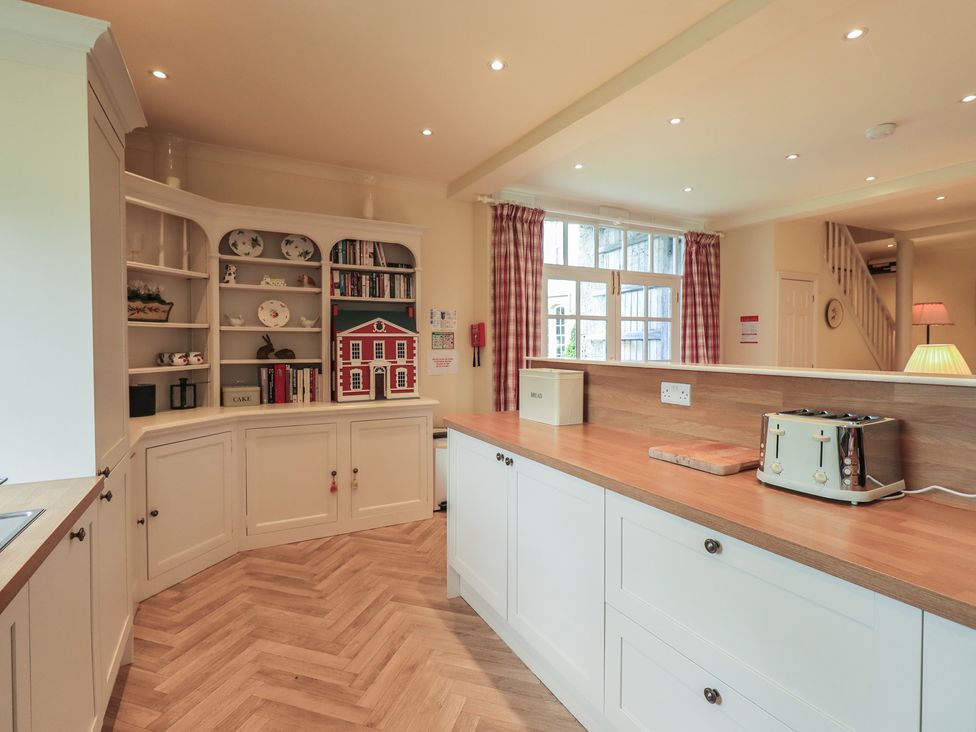 A kitchen with cabinets and a toaster at The Garden Rooms Lawkland in Austwick