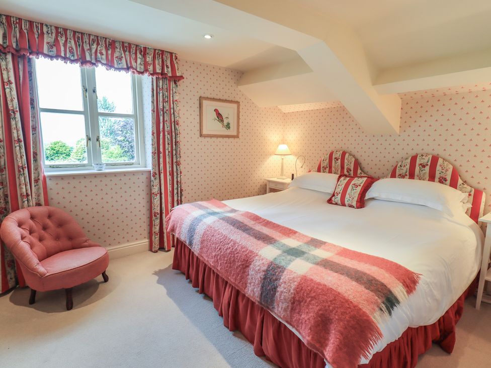 A bedroom with a large bed and a chair at The Garden Rooms Lawkland in Austwick