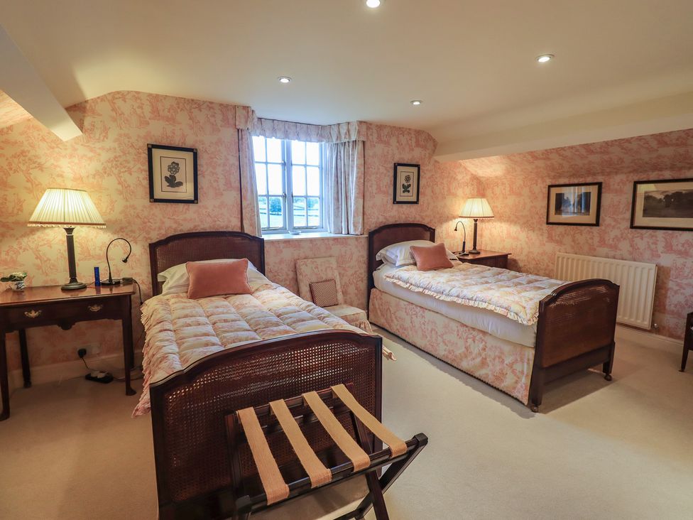 A bedroom with two beds, a lamp, and a window at The Garden Rooms Lawkland, Austwick