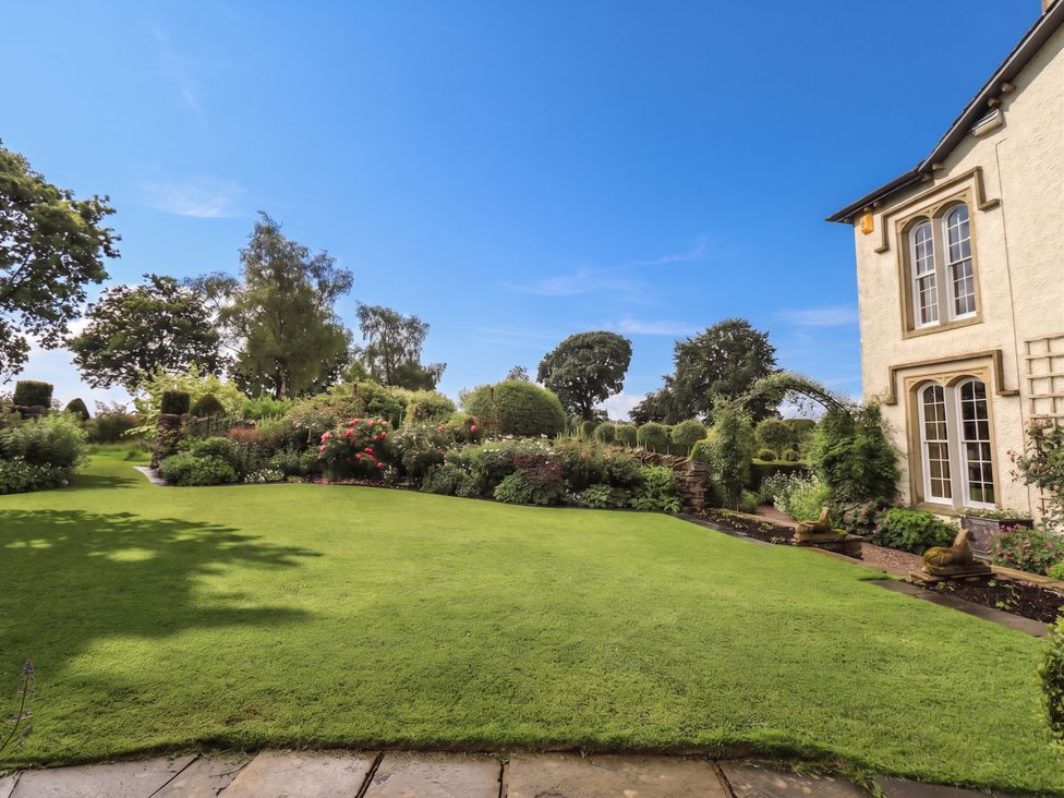 A garden with a lawn and flower beds at The Garden Rooms Lawkland in Austwick