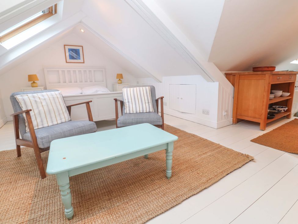 A bedroom with a bed, chairs, and a table at Badgers Loft in Sennen Cove