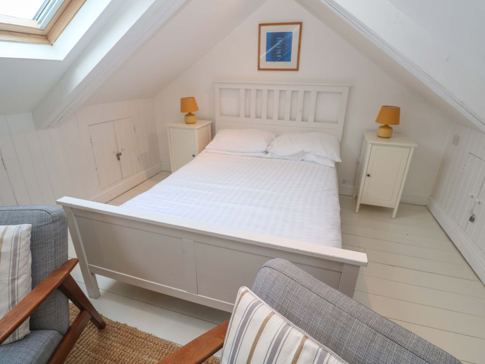 A bedroom with a bed and armchair at Badgers Loft in Sennen Cove