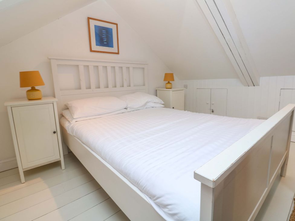 A bedroom with a bed and bedside tables at Badgers Loft Sennen Cove