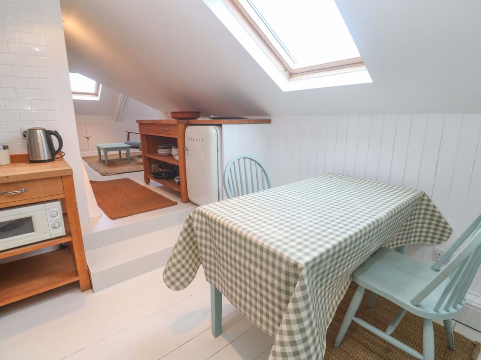 A kitchen with a table, chairs, and appliances at Badgers Loft in Sennen Cove