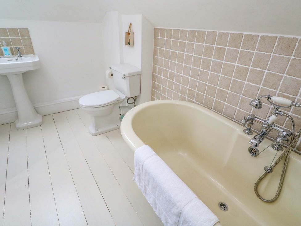 A bathroom with a bathtub, toilet, and sink at Badgers Loft in Sennen Cove