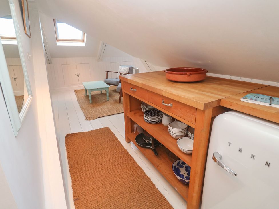 A kitchen with a wooden countertop, dishes, and a refrigerator at Badgers Loft in Sennen Cove