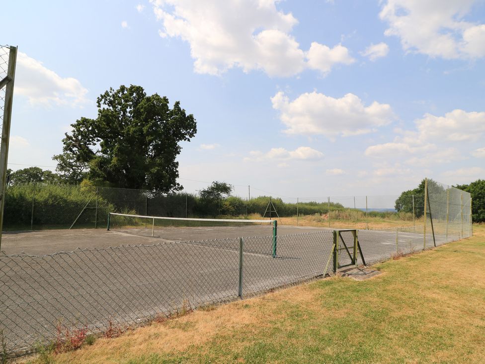 A tennis court with a net and fence at The Cider Press, Motcombe, Shaftesbury