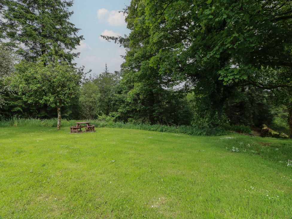 A garden with a picnic table and trees at Corrafeckloch Forest Cottages Glentrool near Newton Stewart