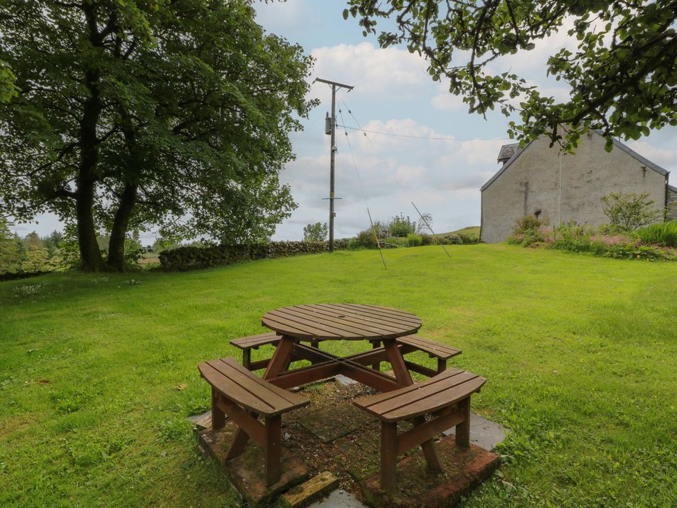 A garden with a picnic table and trees at Corrafeckloch Forest Cottages in Glentrool near Newton Stewart