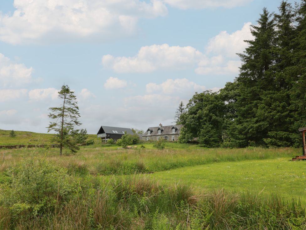 A house and trees in a field at Corrafeckloch Forest Cottages in Glentrool near Newton Stewart