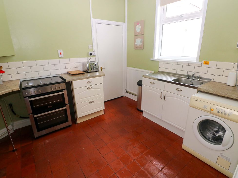 A kitchen with oven, sink, and washing machine at White Thorns in Haverfordwest