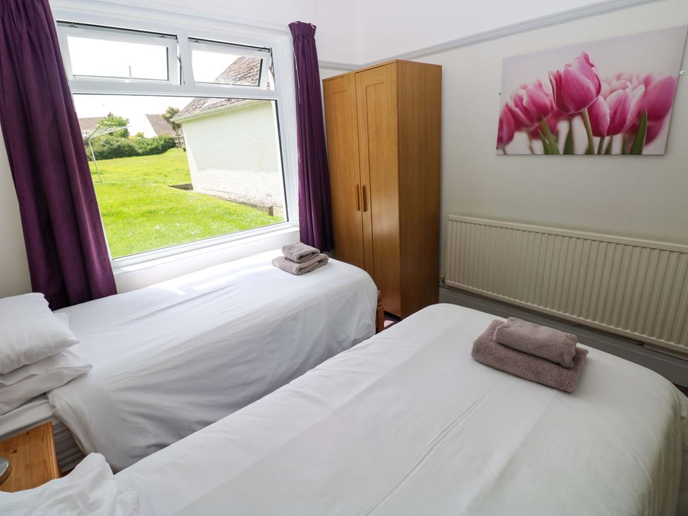A bedroom with two beds and a wardrobe at White Thorns in Haverfordwest