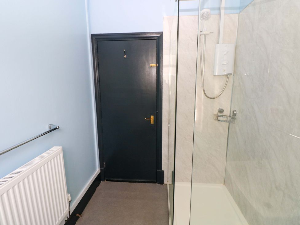 A bathroom with a shower and door at White Thorns in Haverfordwest