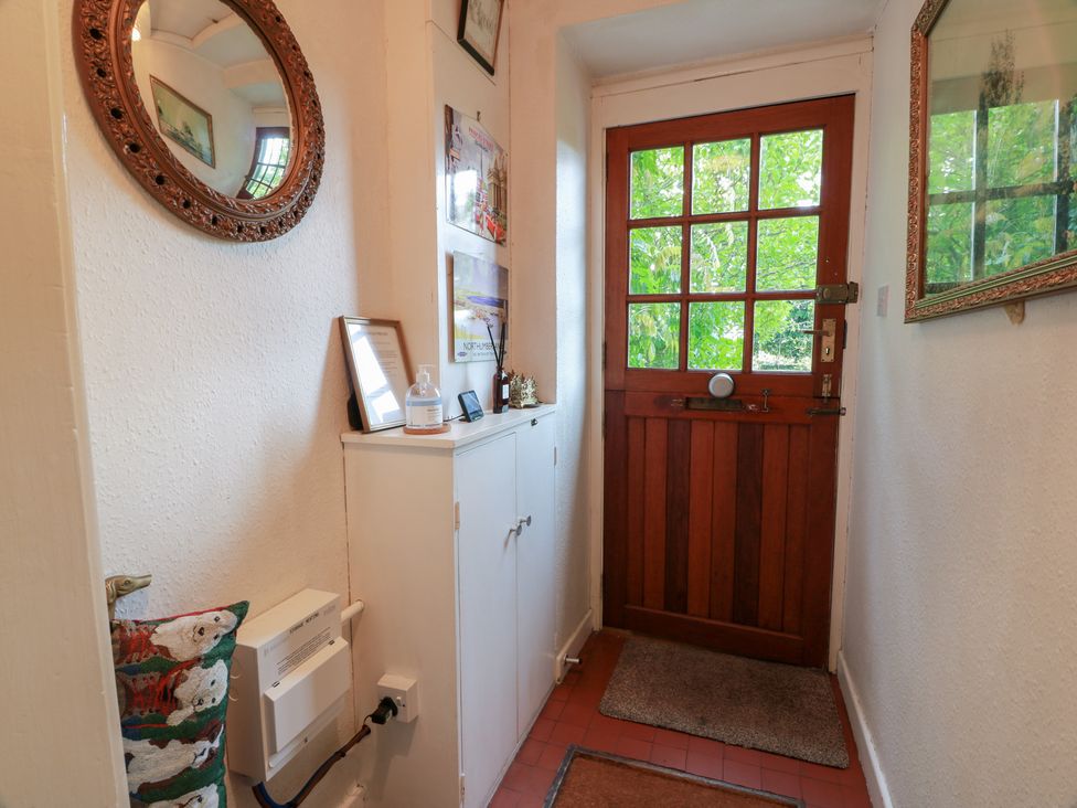 A hallway with a wooden door and a cabinet at Charlies Cottage in Swinton