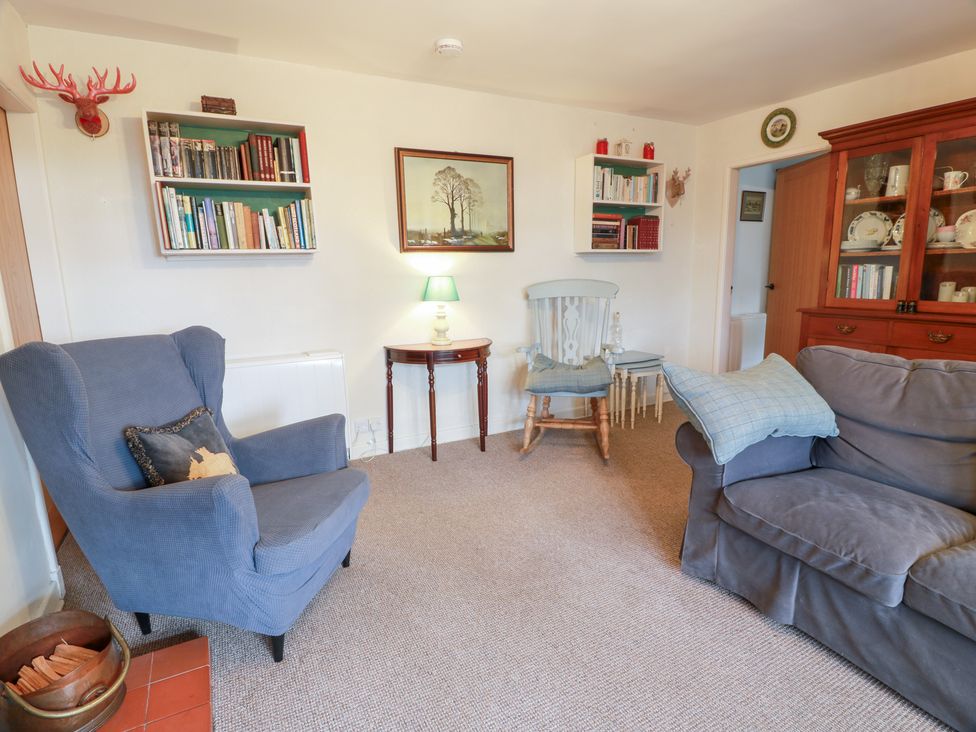 A living room with an armchair, sofa, and bookshelf at Charlies Cottage in Swinton