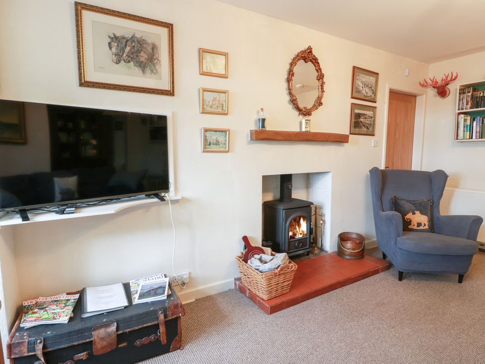A living room with a fireplace and television at Charlies Cottage in Swinton