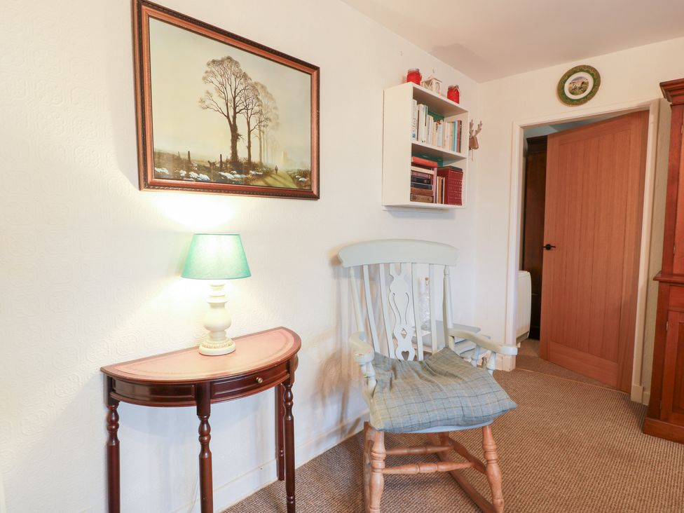A living room with a rocking chair and a bookshelf at Charlies Cottage in Swinton
