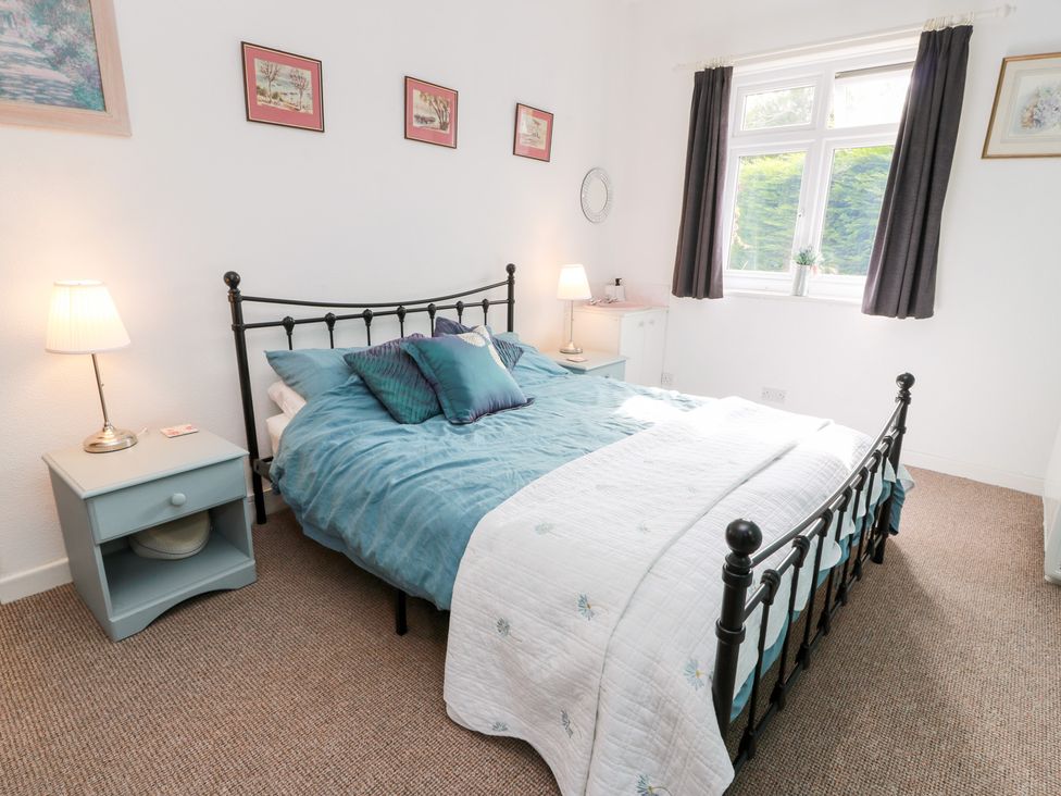 A bedroom with a bed and bedside table at Charlies Cottage in Swinton
