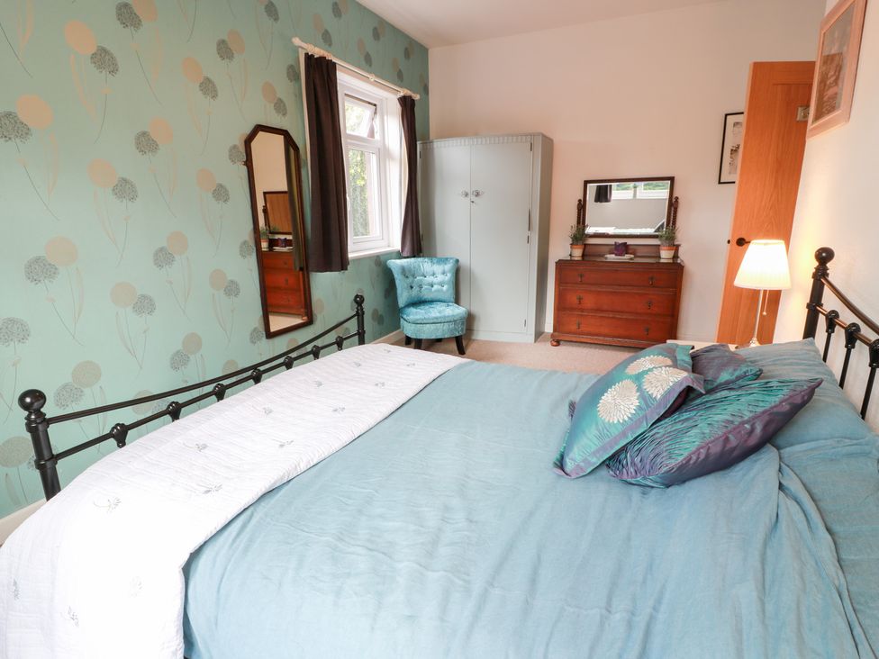 A bedroom with a bed and a wardrobe at Charlies Cottage in Swinton