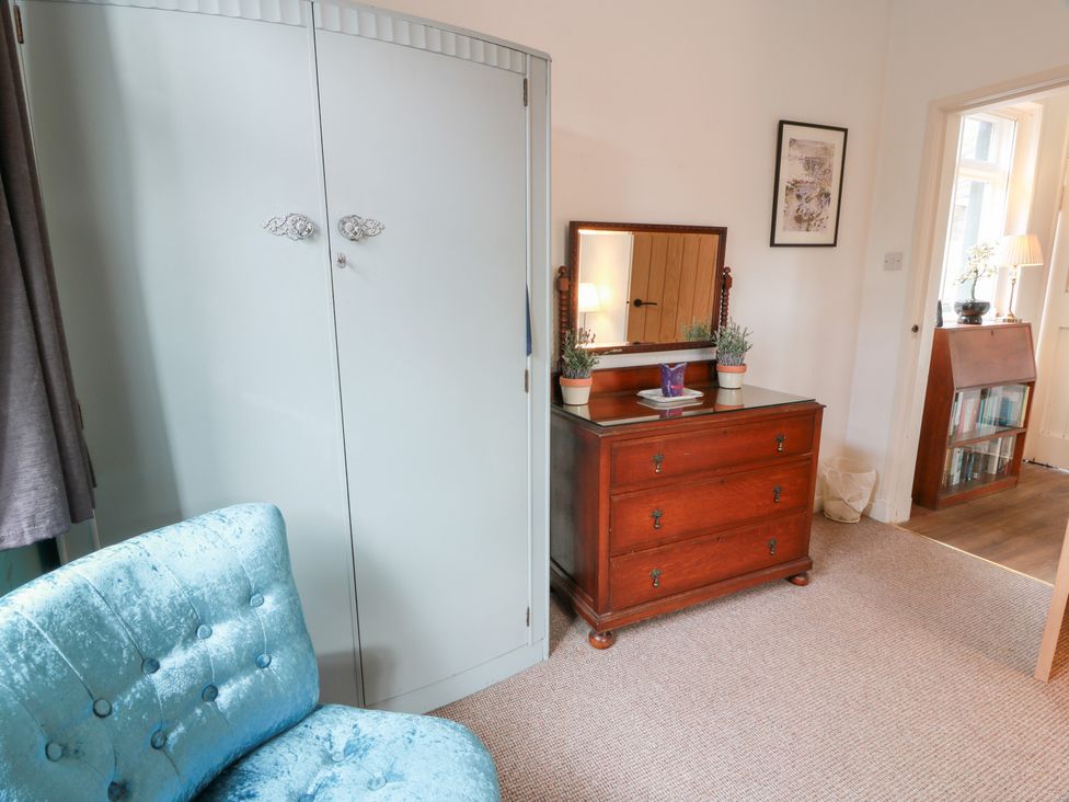 A bedroom with a wardrobe, chest of drawers, and chair at Charlies Cottage in Swinton