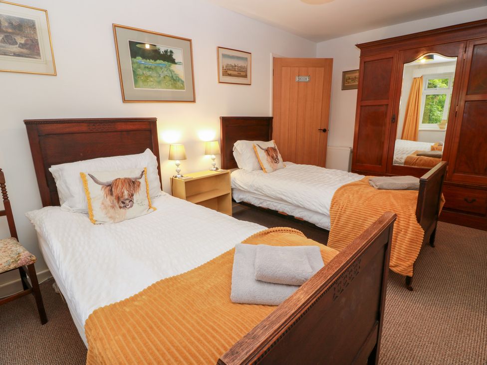 A bedroom with two beds and a wardrobe at Charlies Cottage in Swinton
