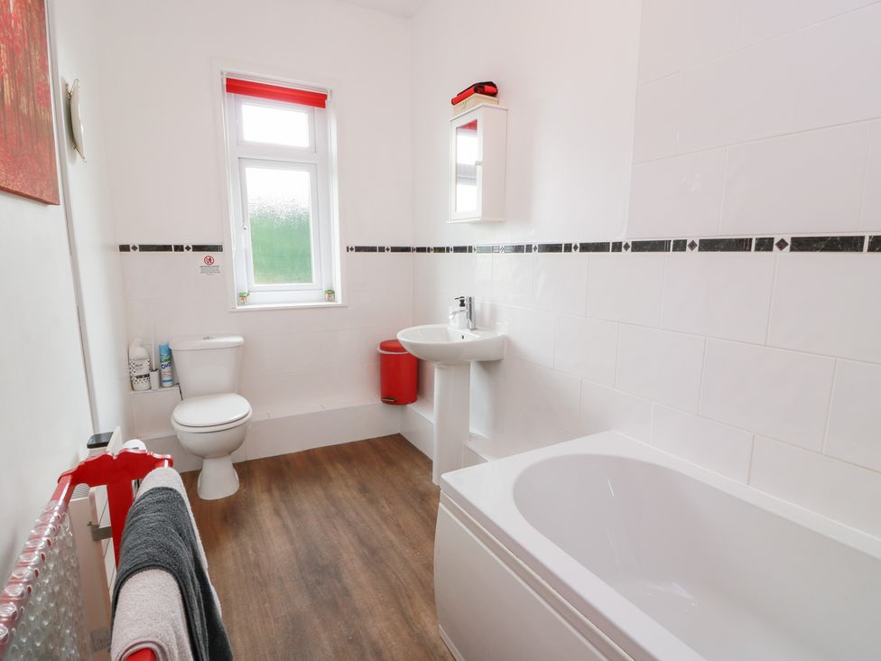 A bathroom with a bath tub, toilet, sink and window at Charlies Cottage in Swinton