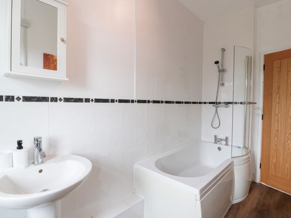 A bathroom with a bath and washbasin at Charlies Cottage in Swinton