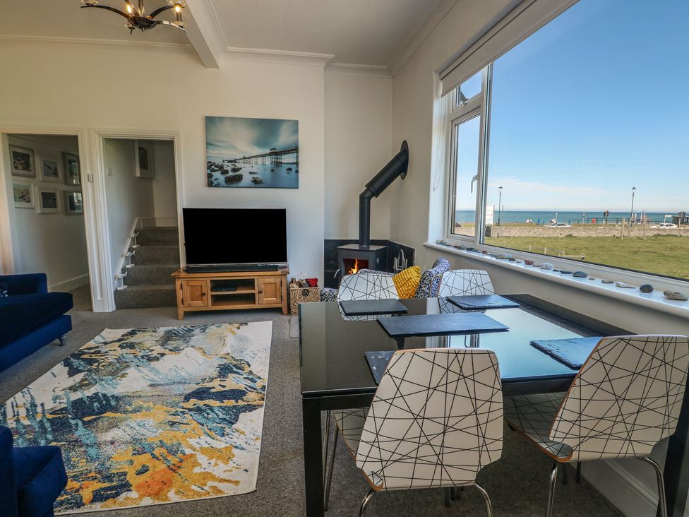 A living room with a tv and dining area at Little Orme View in Llandudno