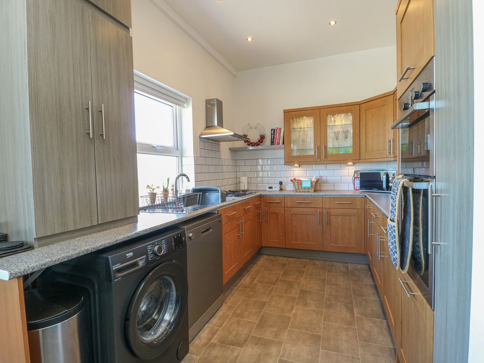 A kitchen with wooden cabinets and appliances at Little Orme View in Llandudno