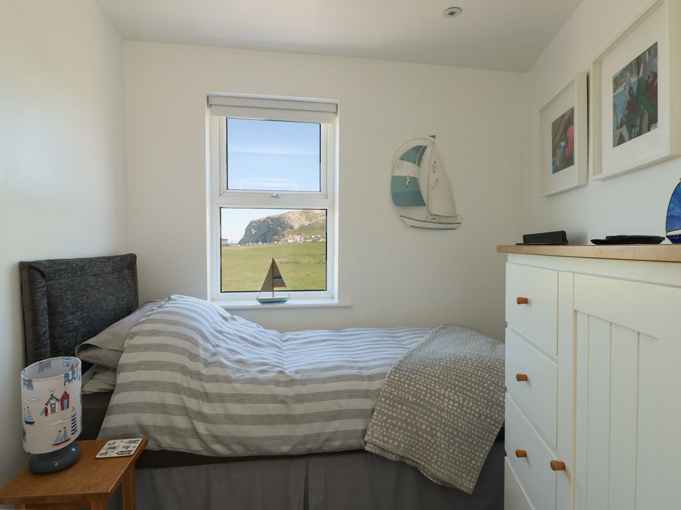 A bedroom with a bed and window at Little Orme View in Llandudno