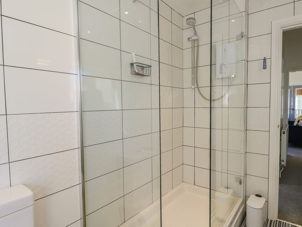 A shower enclosure with a showerhead and a toilet at Little Orme View in Llandudno