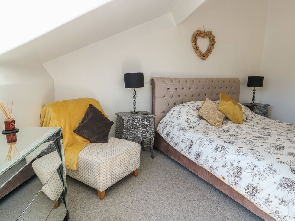 A bedroom with a bed and armchair at Little Orme View in Llandudno
